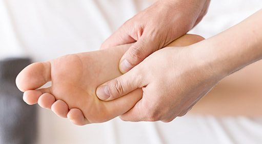 Fizioterapeut drži bolnu petu na pacijentovom stopalu.