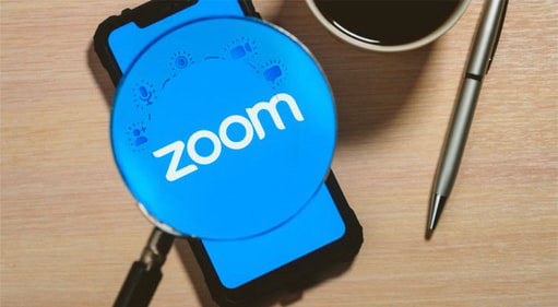 Mobilni telefon na stolu na kojem je otvorena Zoom aplikacija. 